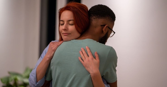 A woman hugging a man supportively.